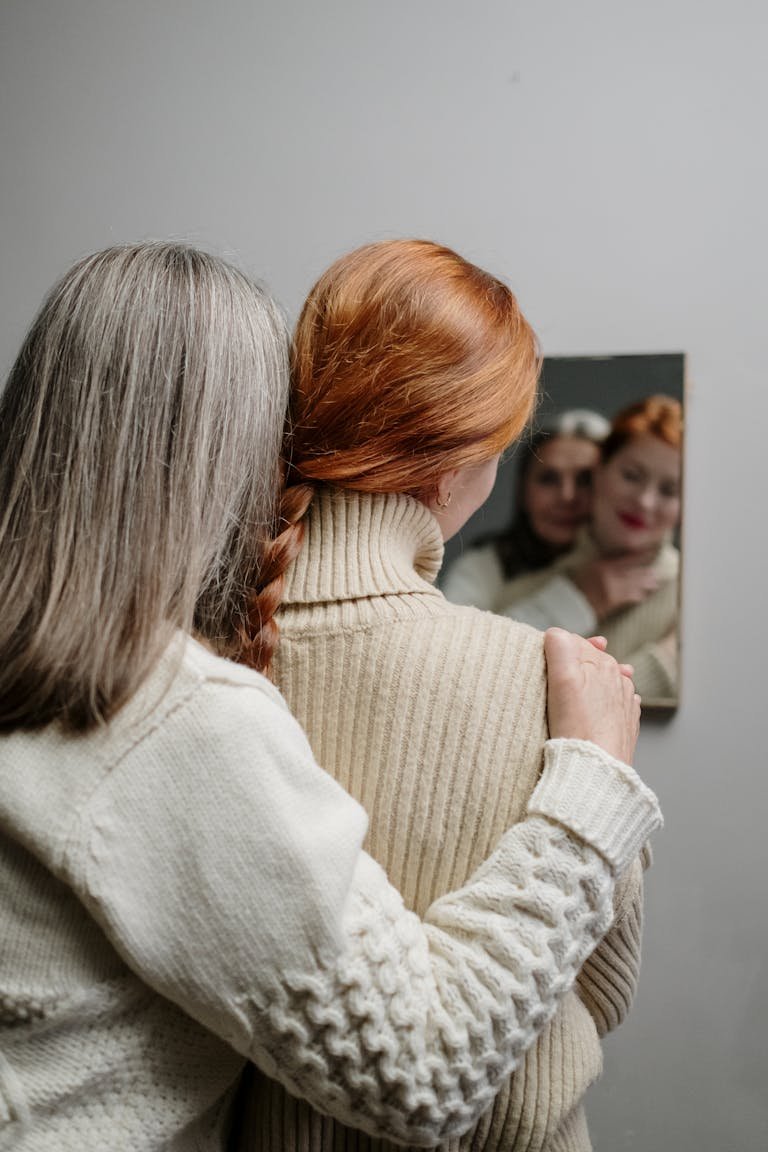 A tender moment between mother and daughter captured in a mirror reflection, showcasing their close bond.