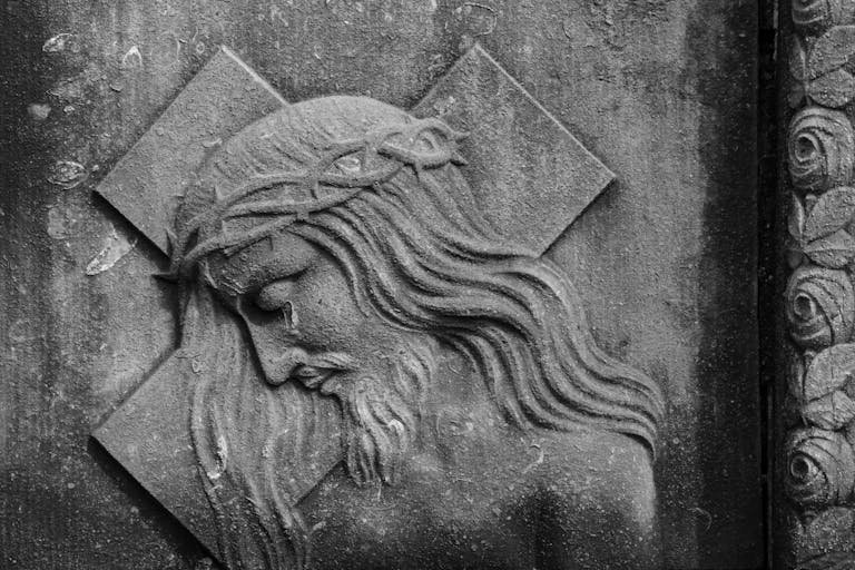 Detailed stone bas-relief of Jesus Christ on a tomb, highlighting religious symbolism.