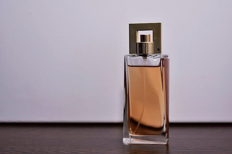 Stylish close-up of a transparent glass perfume bottle on a wooden surface.