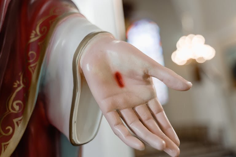 Detailed image of a religious statue's hand with visible stigmata, symbolizing faith.
