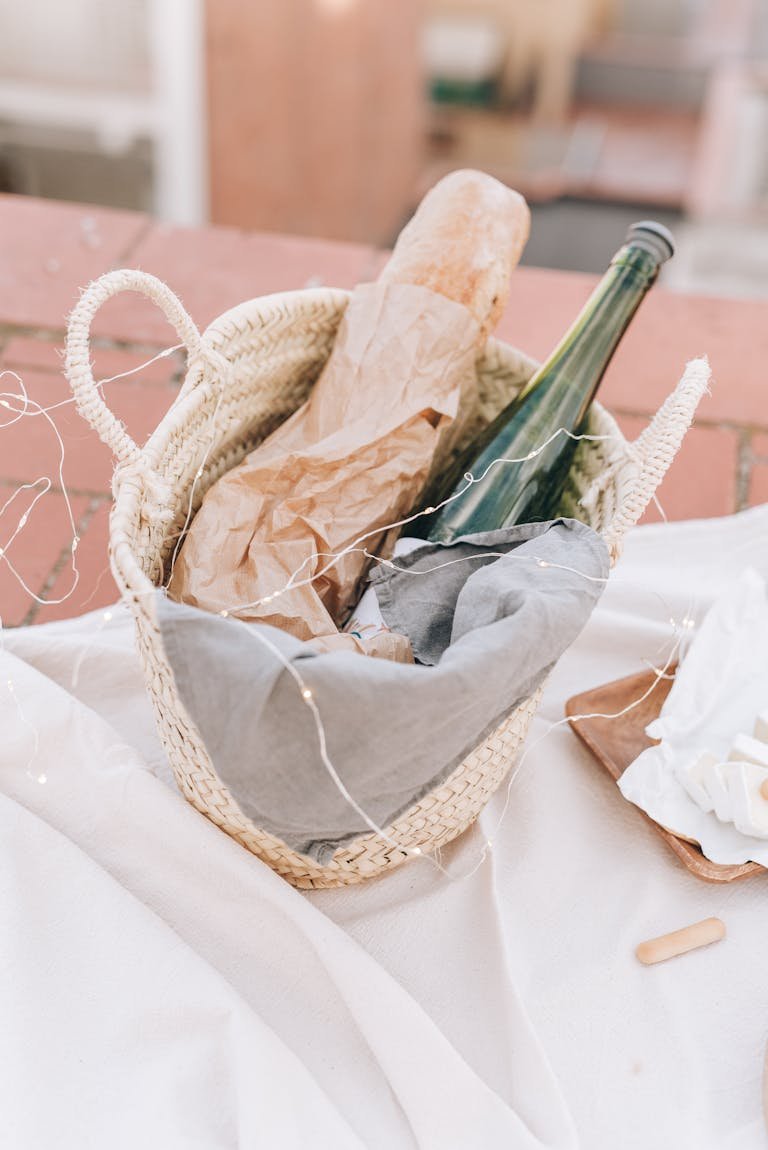 Stylish still life featuring a baguette and wine bottle in a woven basket, perfect for picnics.
