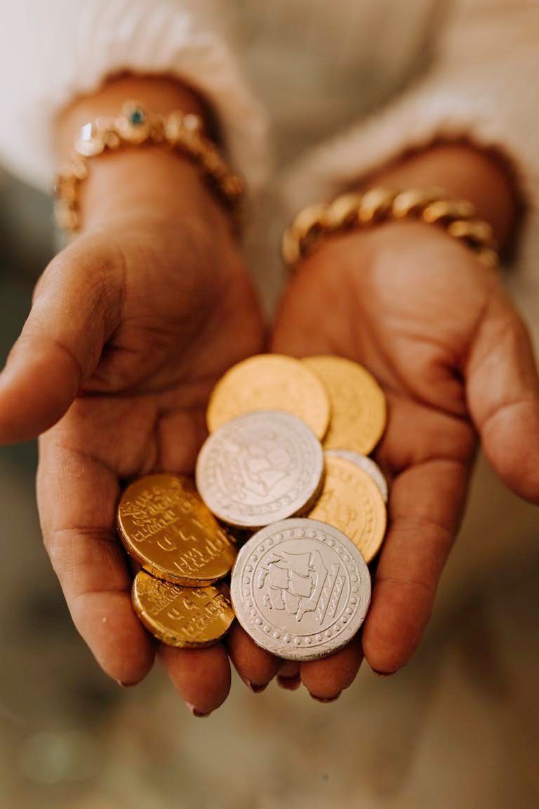 Close-up of hands holding golden and silver Hanukkah gelt coins, symbolizing tradition.