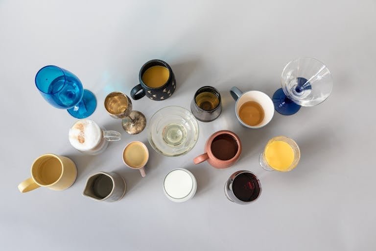 Top view of assorted beverage cups and glasses on a gray surface showcasing variety.